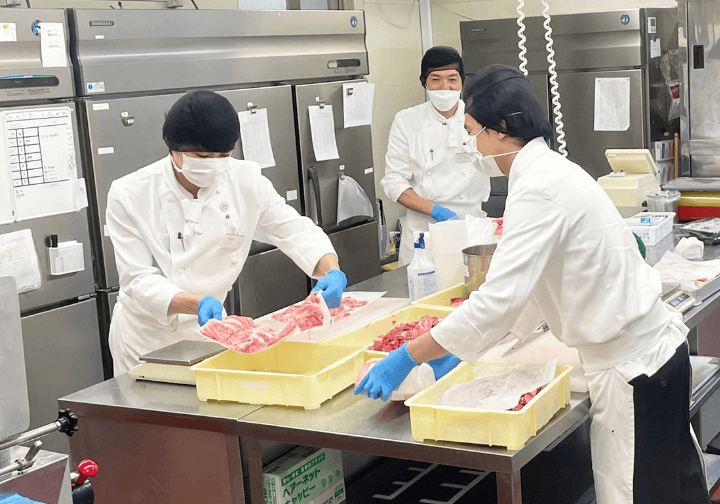 厨房で仕込みをする男性社員達