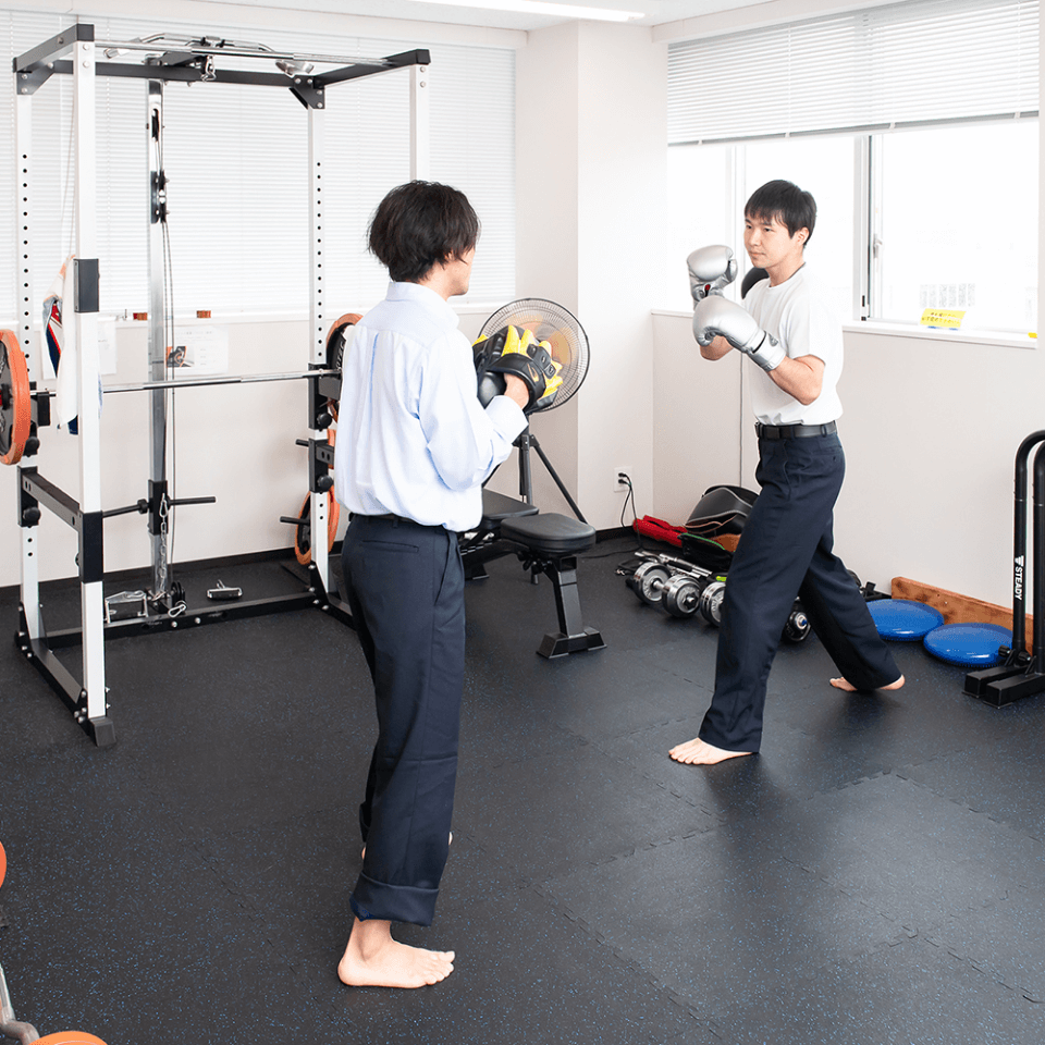 トレーニングルームで体を動かす男性社員たち