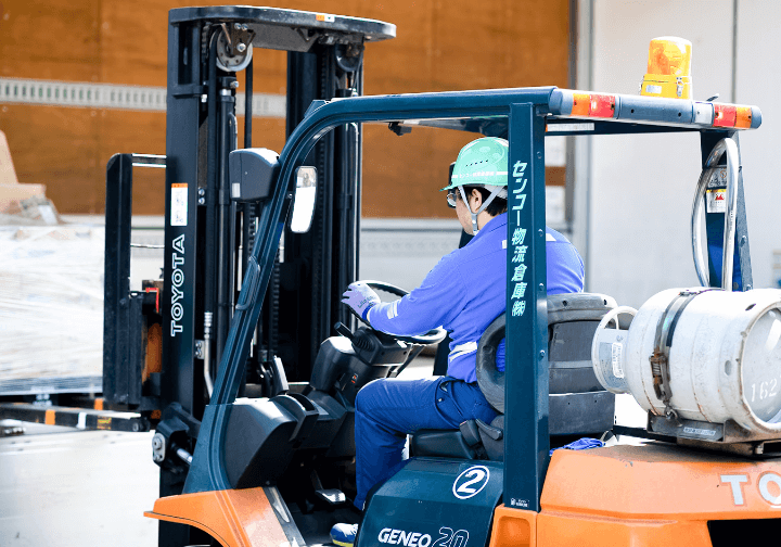 フォークリフトで荷物を運ぶ男性スタッフ