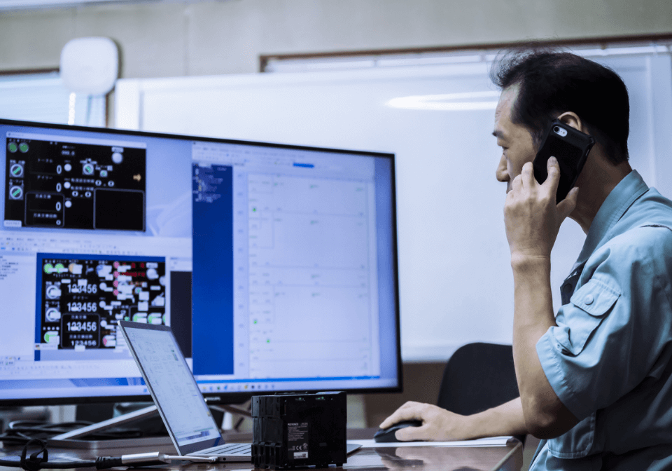 PCをチェックしながら電話対応している男性スタッフ