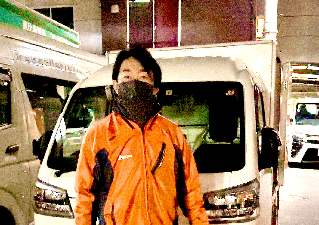 トラックの前に立つ男性ドライバー