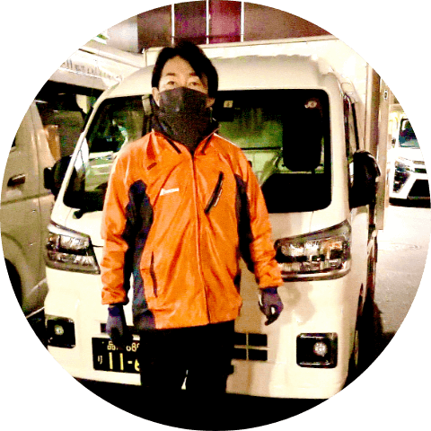 トラックの前に立つ男性ドライバー