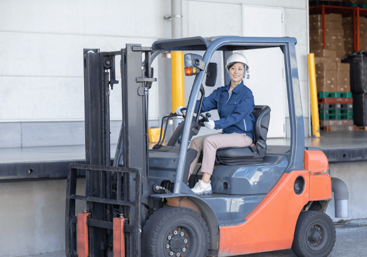 笑顔で運転する女性荷作業員